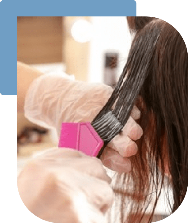 Close-up of a Doctor's hands wearing gloves, combing through a section of a client’s dark hair with a pink and black comb. Doctor is providing treatment for hair problems.