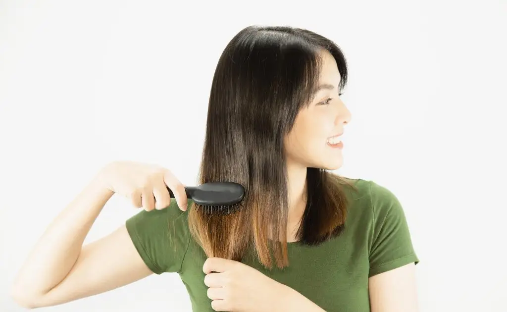 A close up look of a women using hairbrush without hair loss and seems happy after hair fall treatment